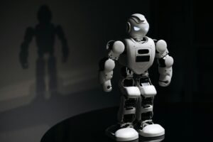 White robot toy casting a shadow in a dark studio setting, highlighting artificial intelligence.