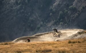 Two cyclists navigate a thrilling downhill trail on a rugged mountainside.