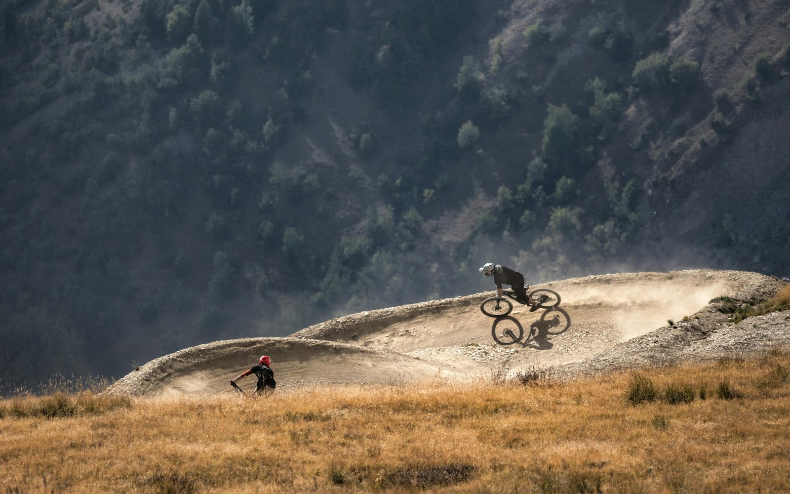 Two cyclists navigate a thrilling downhill trail on a rugged mountainside.