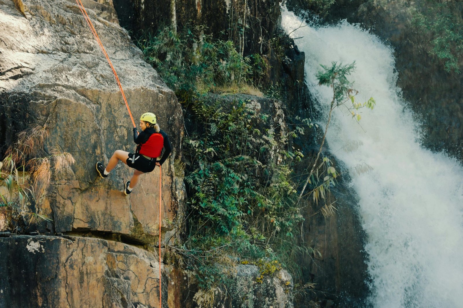 Thrilling outdoor rock climbing by a waterfall showcasing adventure and nature.
