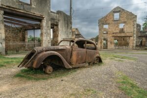 A rusted vintage car in the historical ruins of Oradour-sur-Glane, France.