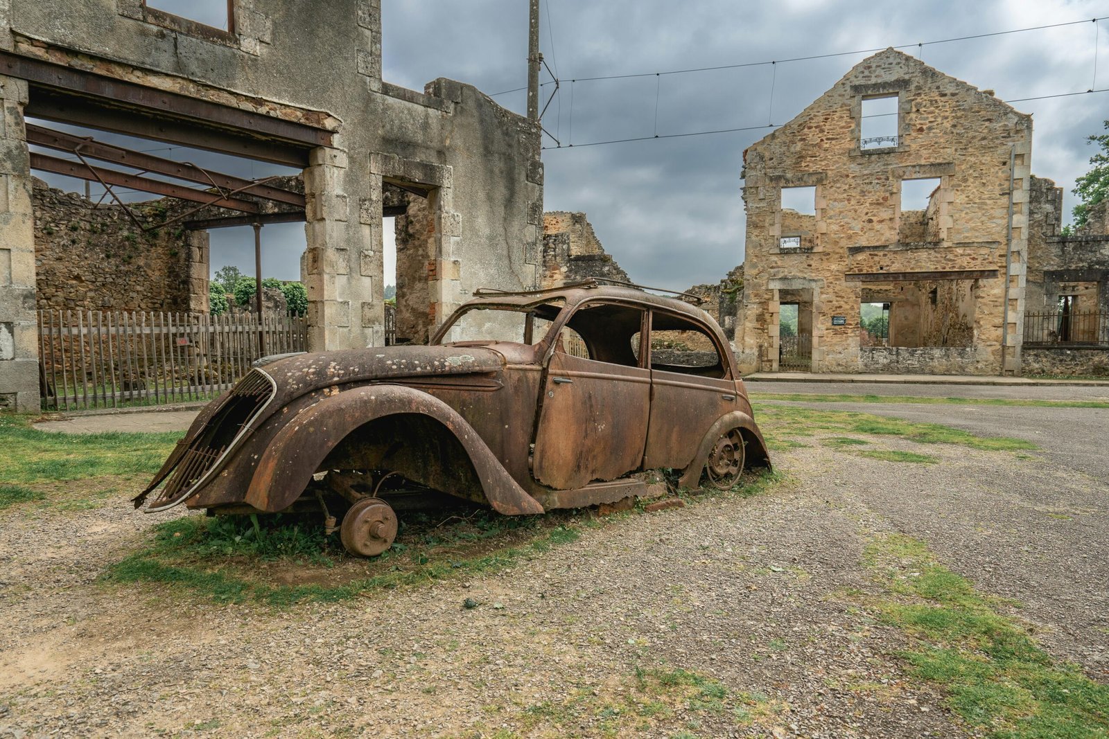A rusted vintage car in the historical ruins of Oradour-sur-Glane, France.