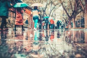 Colorful umbrellas create vibrant reflections on a rainy street in Beijing, China.