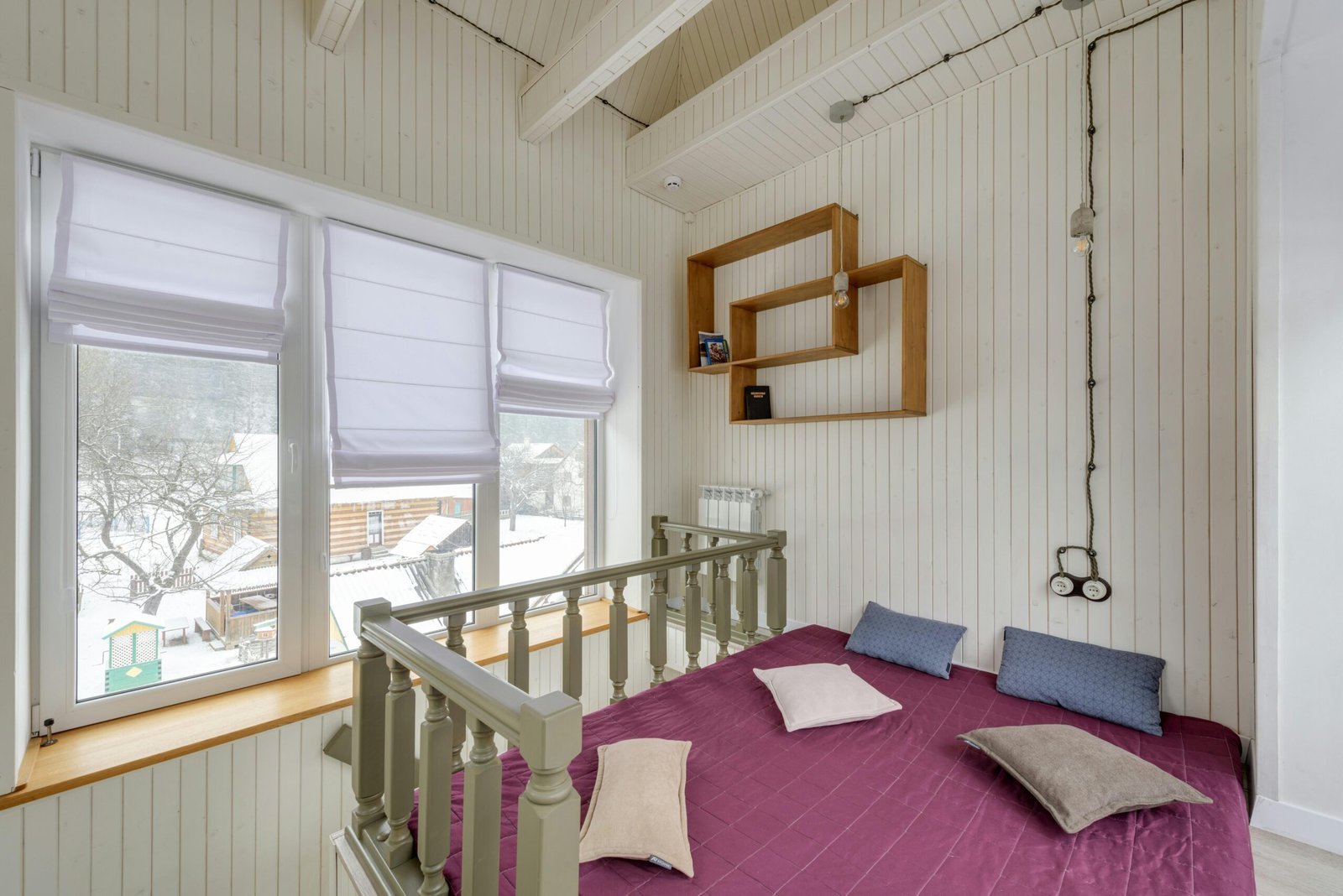 Bright chalet interior with white walls and snowy outdoor view through windows.