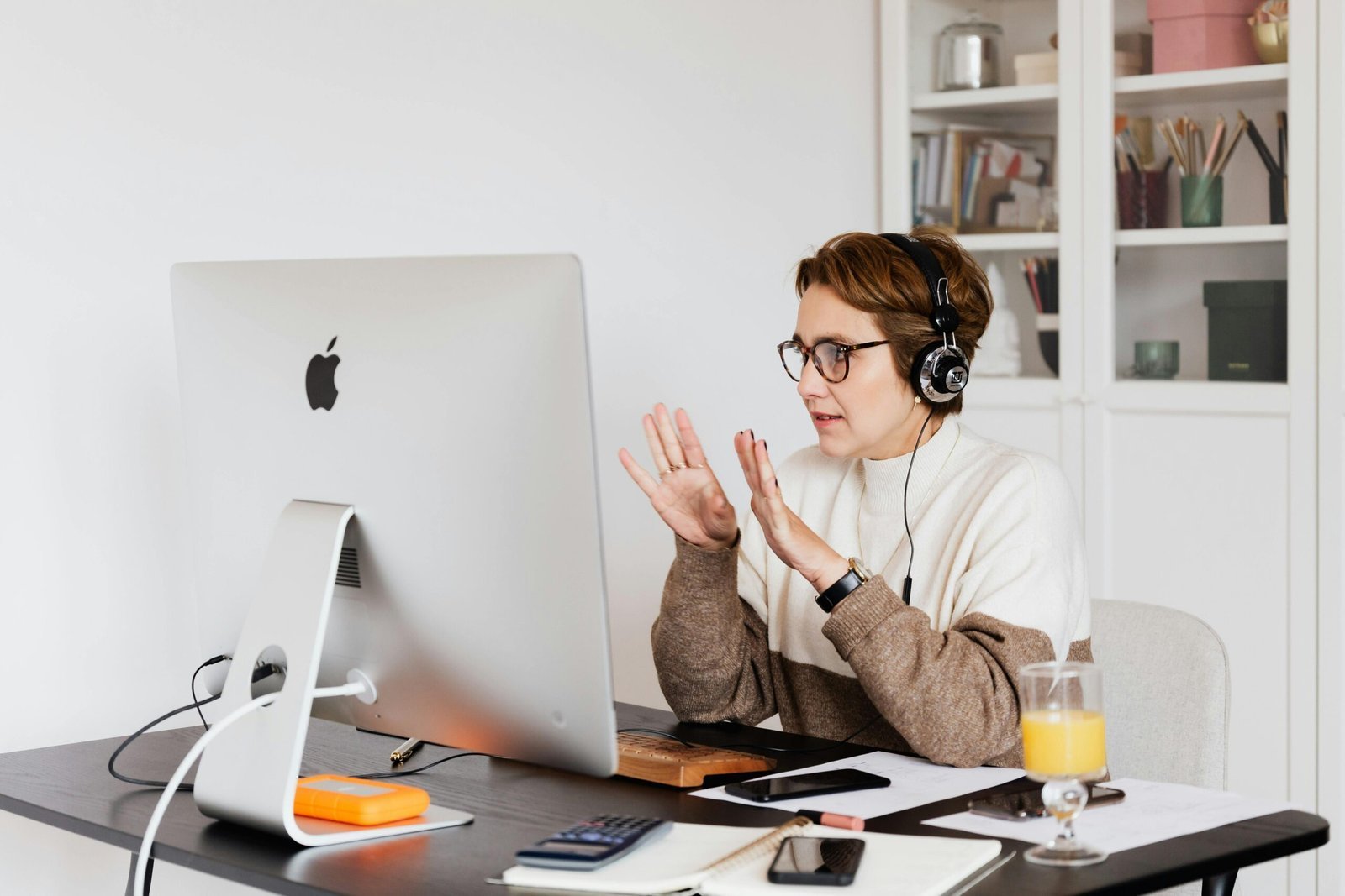 Professional woman wearing headphones conducts video call in a modern workspace, focused on communication.