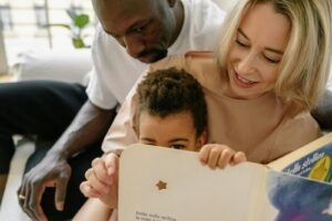 Interracial family enjoying quality time reading a book indoors together.