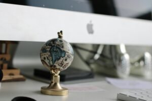A miniature globe sits on a desk in front of an iMac, creating a modern and creative workspace vibe.