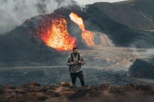 A man explores near a volcanic eruption in Iceland, displaying the raw power of nature.