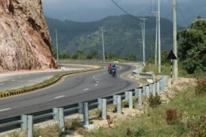 Enjoy a scenic motorcycle ride on a winding road through Nepal's mountains under a clear sky.