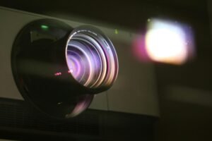 Detailed view of a projector lens emitting light, showcasing optical technology.