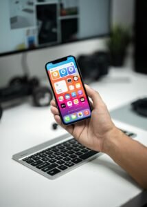 Person holding a smartphone in a modern tech workspace, showing home screen apps.