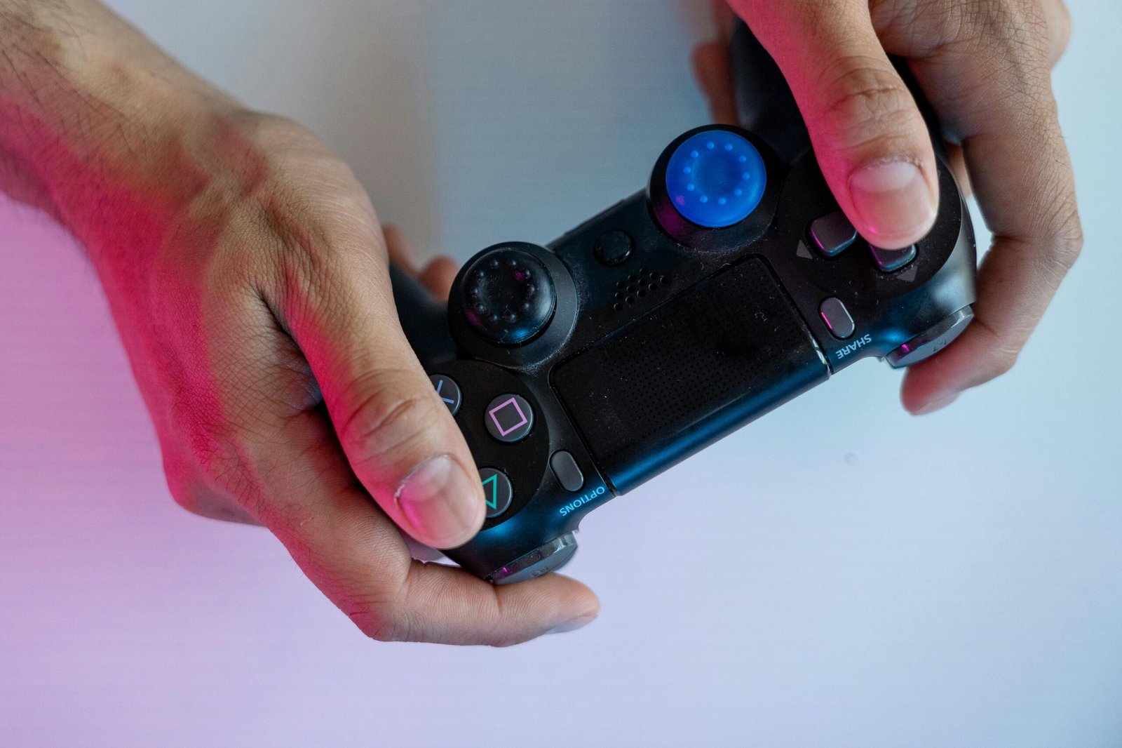 Hands gripping a modern video game controller with colorful lighting effect, highlighting gaming culture.
