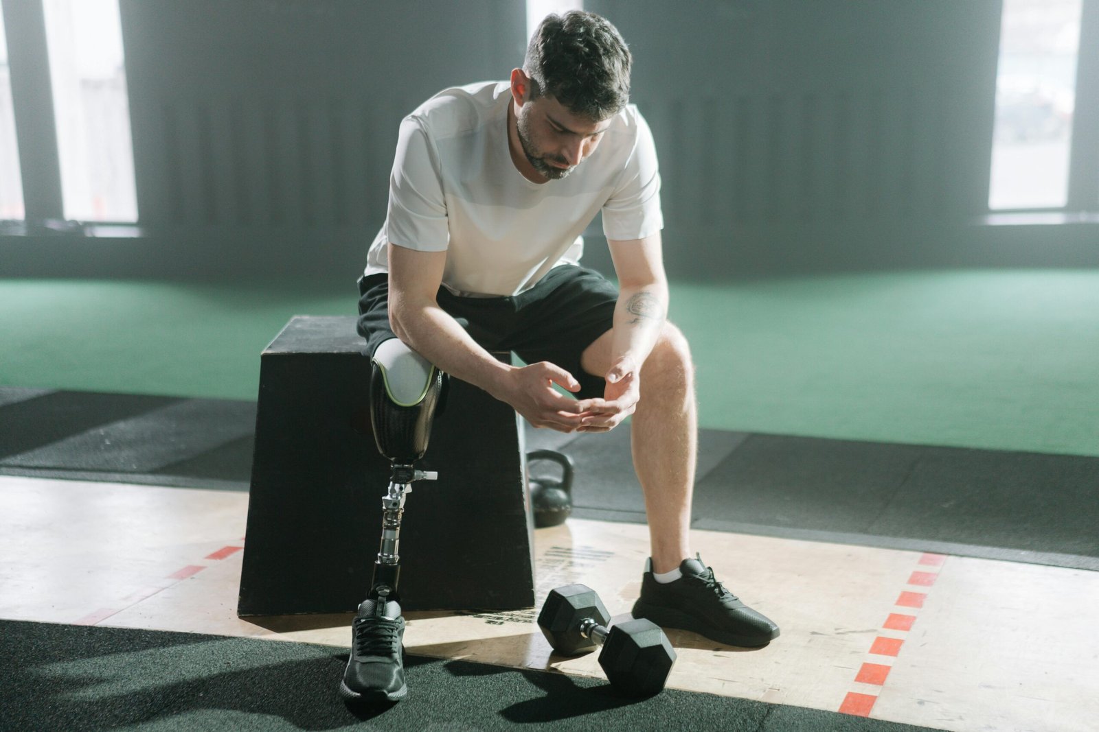 Inspirational portrait of a male athlete with a prosthetic leg sitting in a gym, embracing the challenge of fitness.