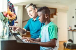 A father guides his son in learning to play the piano, fostering a love for music.