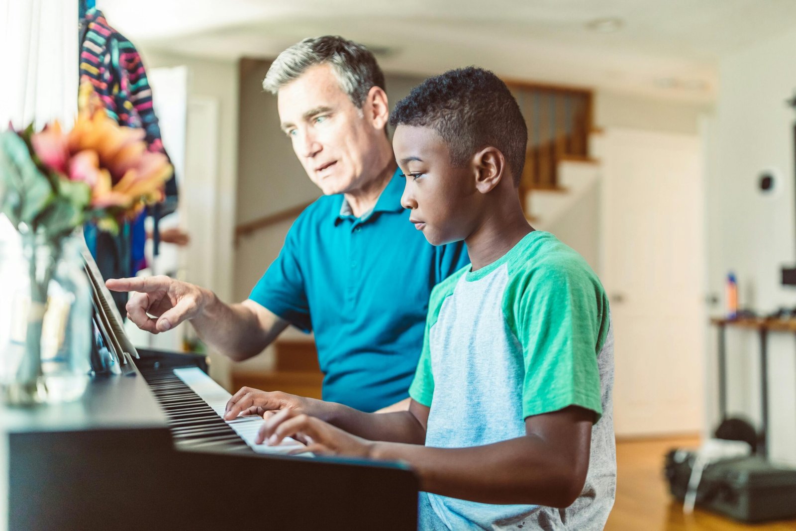 A father guides his son in learning to play the piano, fostering a love for music.