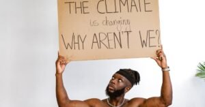 Shirtless African American man holding a climate change awareness sign.