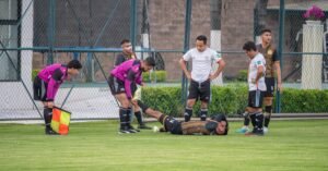 Soccer player injured on the field with teammates and referee assistance in Texcoco, Mexico.