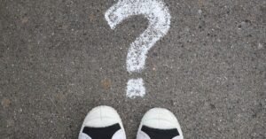 Sneakers on pavement with a chalk question mark, symbolizing curiosity or decisions.