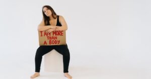 Woman holding 'I am more than a body' sign, promoting empowerment and equality.