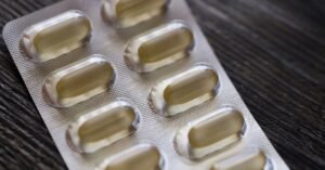 Detailed view of a blister pack with transparent capsules on a textured wooden background.