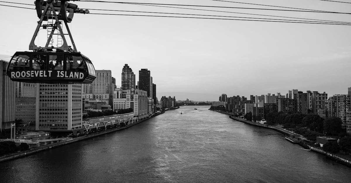 Black and white view of Roosevelt Island tram crossing the East River with a city skyline backdrop.