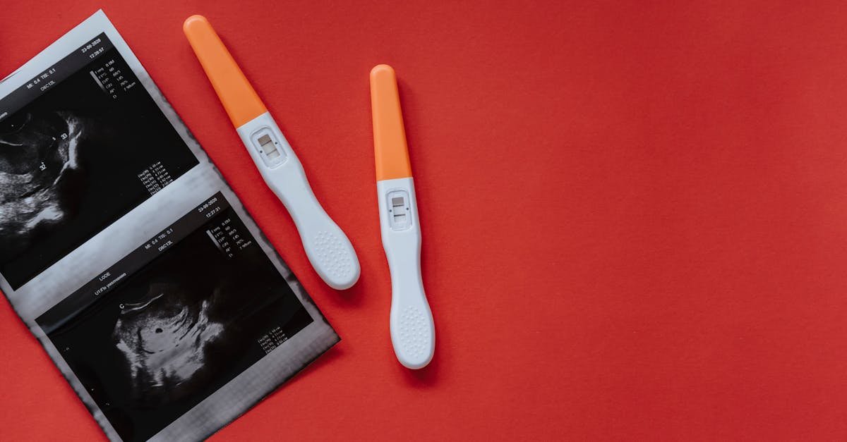 A flat lay of two pregnancy tests and ultrasound images on a red background, conveying anticipation and excitement.