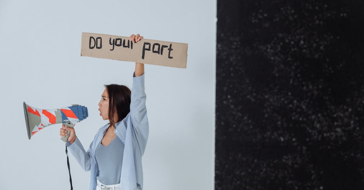 Woman holding a sign and megaphone in a studio setting, encouraging action.