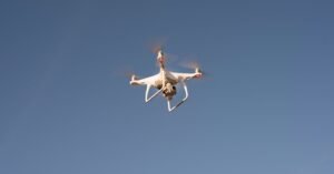 Capture of a white drone flying against a clear blue sky, showcasing modern technology.