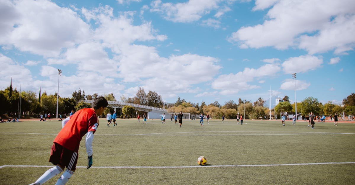 Soccer players on a field under a bright blue sky, competing in a friendly match.
