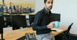 Professional man enjoying a cup of coffee while taking a break in a modern office setting.