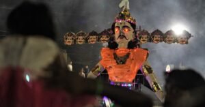 A dramatic nighttime Dussehra festival scene featuring a large illuminated Ravana effigy.