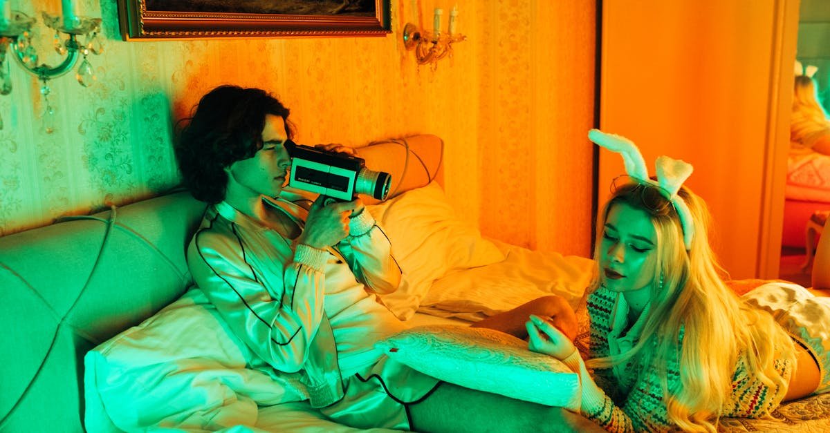 Stylish young couple in bed with retro camera and bunny ears, creating a vintage vibe.