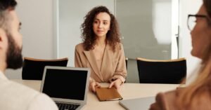 A woman in a business suit participates in a job interview, showcasing professionalism and modern office environment.