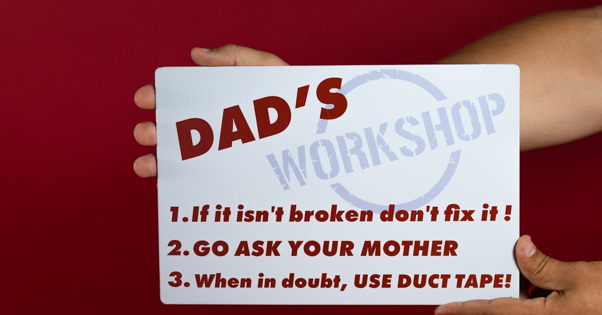 Close-up of a humorous sign with Dad's workshop rules on a red background held by hands.