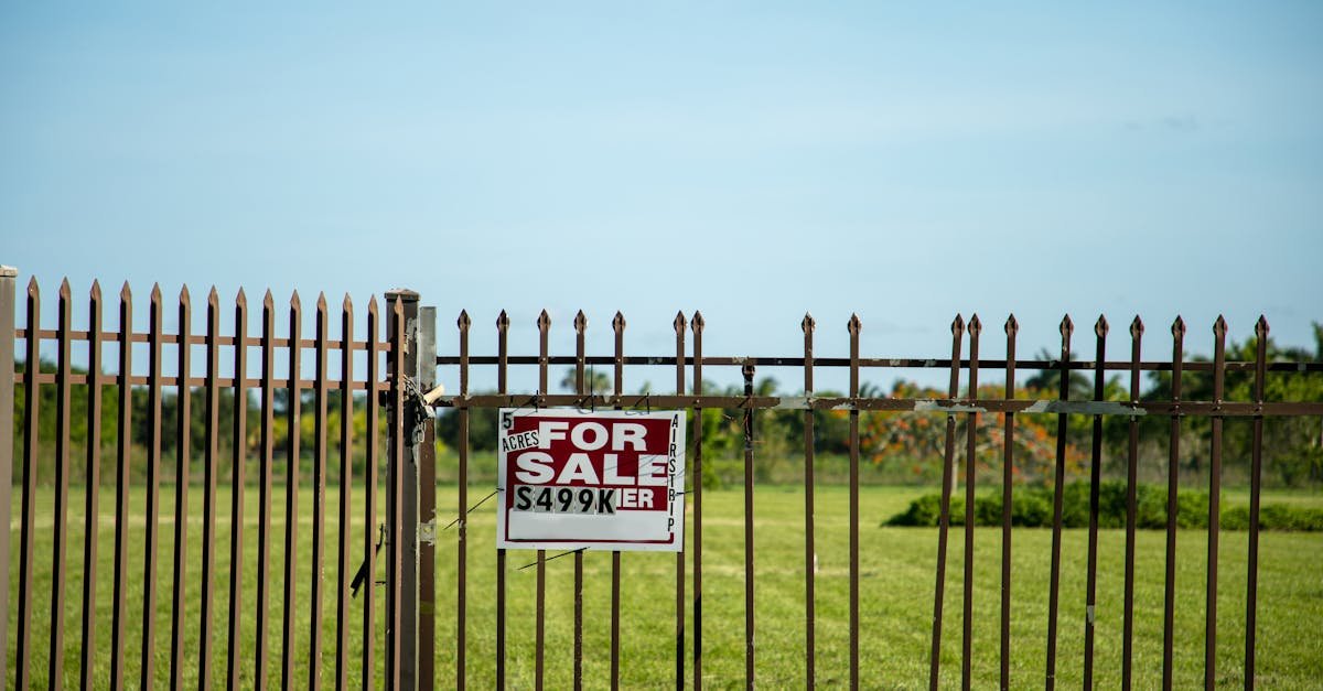 A large plot of land bordered by an iron fence, complete with a 'For Sale' sign in Miami, FL. Ideal for development.